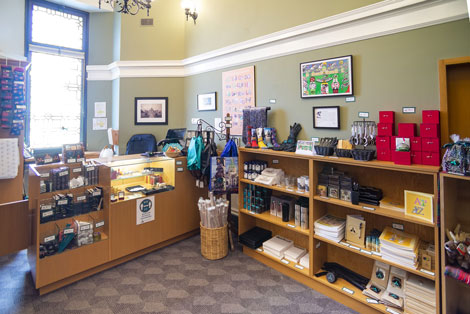View inside the Gift Shop: items for sale neatly displayed on front desk and wooden shelving
