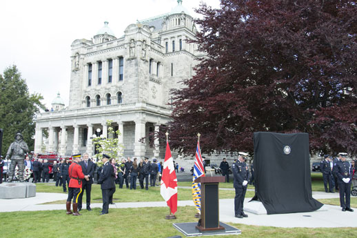 Police officers gather behind the Parliament Buildings at a memorial.