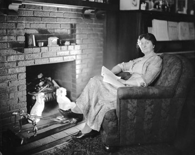 Portrait of Mary Ellen Smith sitting in a chair with a book. Caption reads, "Mary Ellen Smith, the first woman elected to the Legislative Assembly"
